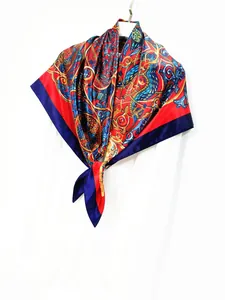 Detail of silk scarf showing vintage paisley pattern in red and gold on a white background