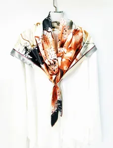 Close-up of silk-like floral scarf with abstract ink patterns and golden buckle detail
