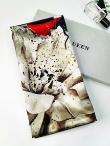 Detailed close-up of floral print silk scarf with gold flecks on an elegant gift box