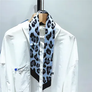 Detail of leopard print twilly scarf in blue and grey silk hanging on a white shirt