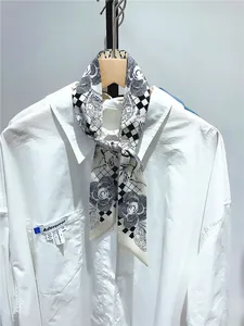 Dettaglio di una sciarpa in seta a fiori e scacchi annodata sul colletto di una camicia