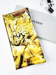 Detailed view of yellow floral silk scarf with artistic patterns and luxury gift packaging