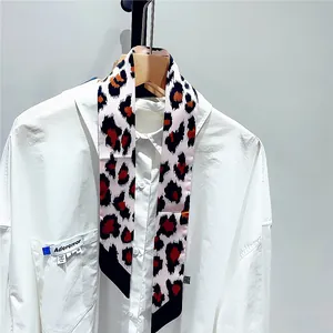 Detail shot of leopard print twilly scarf tied on a white cotton shirt sleeve