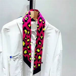 Close-up of pink leopard print skinny silk scarf tied on a white shirt collar