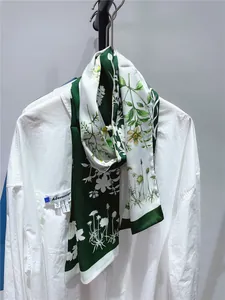 Détail d'un foulard en soie à imprimé floral vert noué élégamment sur un col de chemise blanc