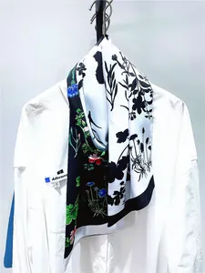 Détail d'un foulard en soie imprimé floral avec motifs noir et blanc sur chemise blanche