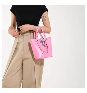 Detalle del bolso tote rosa punk con remaches metálicos plateados y colgante de cruz