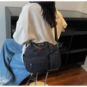 Détail du sac à bandoulière noir multi-poches avec poignées en cuir marron et style urbain