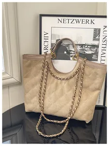Detail of beige quilted tote bag with matte finish and circular handles on mirror surface