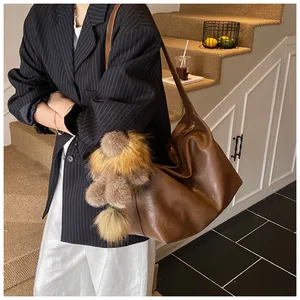 Dettaglio di una grande borsa hobo in pelle marrone con un simpatico ciondolo a orsetto