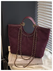 Detail of burgundy quilted tote bag with golden chain strap on decorative background