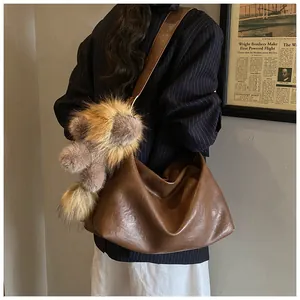 Dettaglio borsa tote in pelle marrone vintage con stile hobo morbido e ciondolo peluche