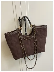 Macro detail of deep brown quilted tote bag in suede texture with golden chain straps