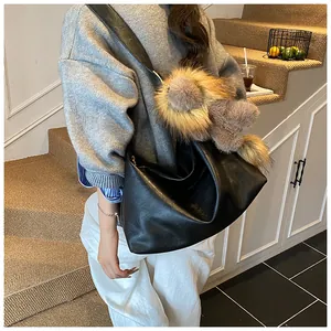 Dettaglio della grande borsa hobo in pelle nera con pompon in pelliccia sulla tracolla