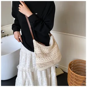 Detail of crochet knit hobo bag with hollow pattern and premium brown leather straps