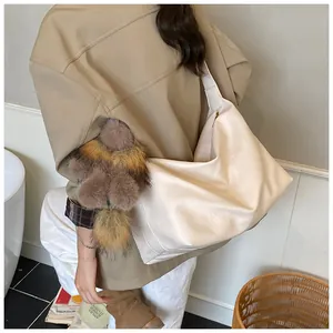 Dettaglio di una grande borsa tote in pelle PU crema con ciondolo decorativo in peluche