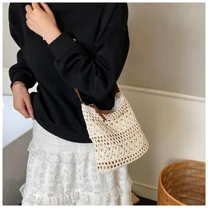 Detail of hand-woven beige crossbody bag with hollow floral pattern and leather strap
