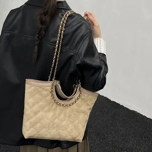 Quilted beige faux suede tote bag with chain strap shown on model in black leather jacket