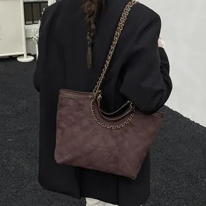 Quilted tote bag in dark coffee suede with gold chain strap shown on a model