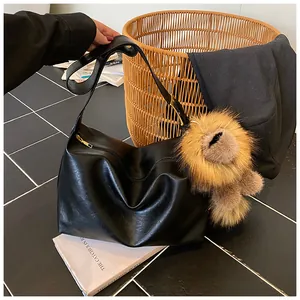 Dettaglio borsa tote in ecopelle nera con ciondolo a cucciolo di peluche marrone