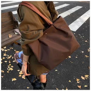 Detail of dark brown waterproof nylon tote bag with leather strap on a shoulder