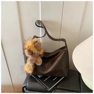 Dettaglio della borsa tote in pelle marrone scuro con ciondolo a forma di peluche