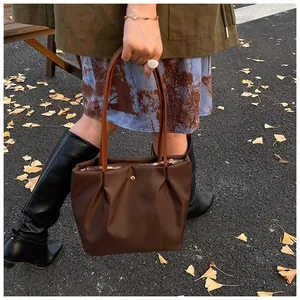 Detail of dark brown ruched nylon tote bag with gold zipper and metallic buckle