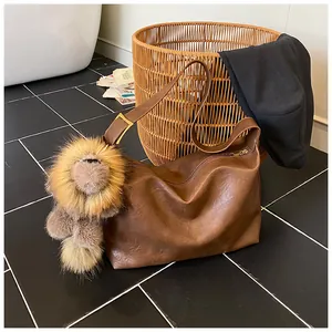 Dettaglio della borsa hobo in pelle marrone con ciondolo a leone di peluche e fibbia dorata