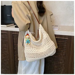 Close-up of woven shoulder bag with hollow crochet pattern and cute doll charm