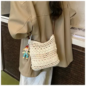 Detail of cream woven shoulder bag with floral patterns and colorful doll pendant charm