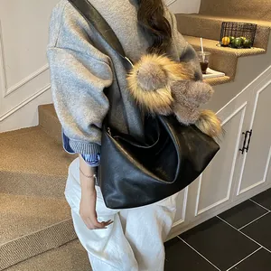 Borsa hobo minimalista in pelle nera con ciondolo a pompon in finta pelliccia colorata