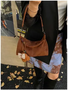 Brown suede hobo bag with a cute teddy bear charm shown on a stylish autumn outfit