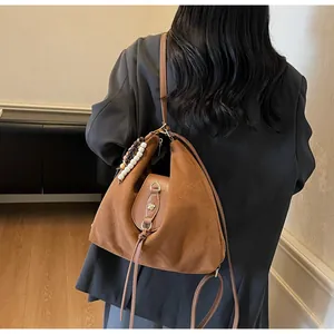 Vue détaillée du sac en daim marron avec perles décoratives et boucle fleurie dorée
