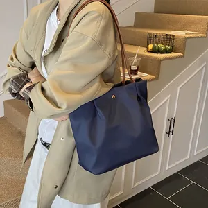 Fashionable dark blue nylon tote bag with brown leather handles and gold metal buckle