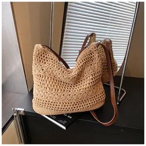Detailed close-up of straw woven tote bag featuring hollow patterns and brown leather straps