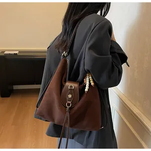 Détail du grand sac hobo marron foncé avec boucle florale et pendentifs en perles de bois