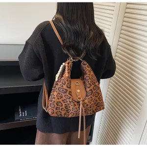 Détail du sac à dos léopard avec franges en cuir marron et boucle dorée en pétale
