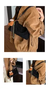Detail of black suede underarm bag featuring a cute teddy bear charm and fringe