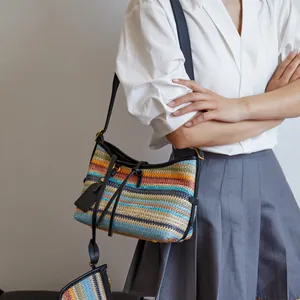 Bohemian striped knit crossbody bag with leather straps and gold metal feet on white shirt