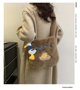 Détail du sac fourre-tout en peluche marron avec broderie et breloque canard blanc
