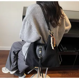 Détail d'un cabas noir mat avec fermoir floral en métal et pompon en perles de bois