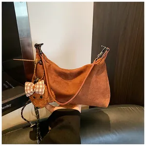 Detailed macro view of the brown frosted suede underarm bag with cute teddy bear charm