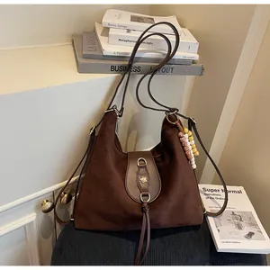 Détail du sac cabas en daim marron avec pendentif artisanal et boucle en cuir
