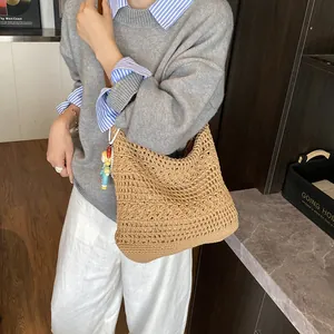 Handcrafted khaki woven tote bag with cutout patterns and a colorful doll pendant