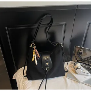 Détail du sac Hobo noir avec breloque en perles de bois et boucle logo fleur dorée