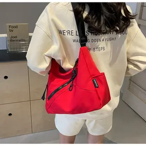 Detail of red canvas crossbody bag with diagonal zipper and adjustable strap