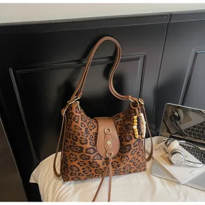 Détail du sac cabas léopard avec lanières en cuir marron et fermoir fleur à franges