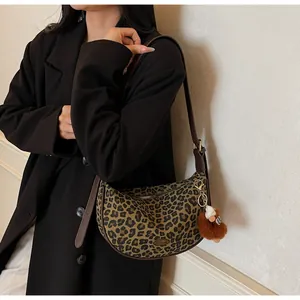 Detailansicht der Schultertasche mit Leopardenmuster, Metallanhänger und Plüschtier
