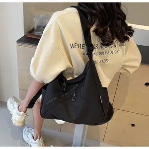 Detail of a black nylon crossbody bag with adjustable strap and front zipper pocket