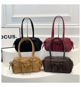 Detalle de bolsos Boston de gamuza con lazos en negro, burdeos, camello y café oscuro